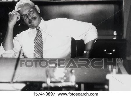 Stock Photo - Portrait of a businessman sitting at his desk. Fotosearch