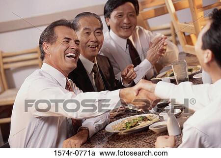 Stock Image - Three business executives seated at a restaurant. Fotosearch