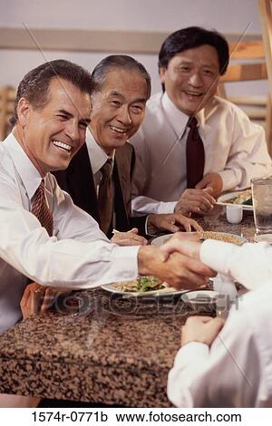 Stock Image - Three business executives seated at a restaurant. Fotosearch