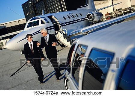 Stock Image - Two businessmen walking together at the airport. Fotosearch