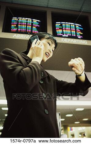 Stock Image - Young businesswoman talking on a mobile phone at the airport. Fotosearch