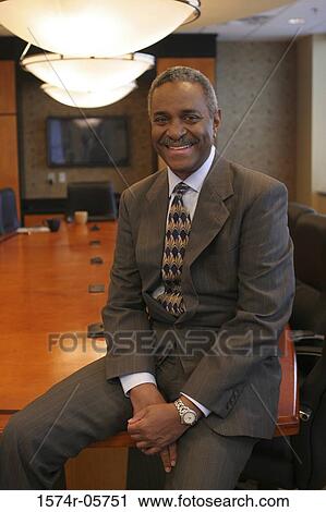 Stock Image - Businessman sitting in a conference room smiling. Fotosearch