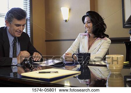 Stock Image - Businessman sitting in an office with a businesswoman. Fotosearch