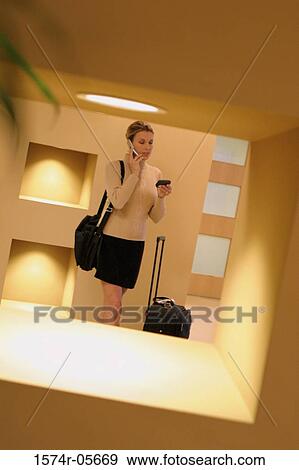 Stock Photo - Businesswoman standing in a corridor using a mobile phone. Fotosearch