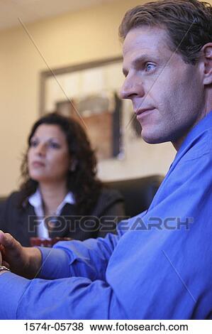Close-up of a businessman and a businesswoman sitting in a conference room View Large Photo Image Stock Photo - Close-up of a businessman and a businesswoman sitting in a conference room. Fotosearch