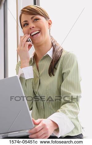 Close-up of a businesswoman holding a laptop using a mobile phone View Large Photo Image Stock Image - Close-up of a businesswoman holding a laptop using a mobile phone. Fotosearch