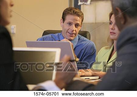 Stock Image - Group of business executives sitting in a conference room. Fotosearch