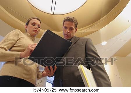 Stock Photography - Low angle view of a businessman talking to a businesswoman. Fotosearch