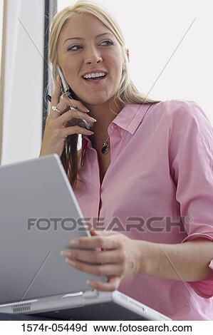 Stock Image - Low angle view of a businesswoman using a mobile phone. Fotosearch