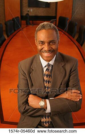 Portrait of a businessman standing in a conference room smiling View Large Photo Image Stock Image - Portrait of a businessman standing in a conference room smiling. Fotosearch