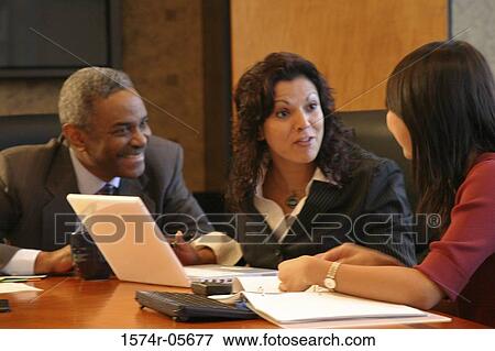 Stock Photo - Two businesswomen and a businessman sitting in a conference room. Fotosearch