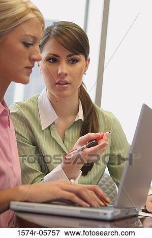 Stock Photo - Two businesswomen sitting in front of a laptop. Fotosearch