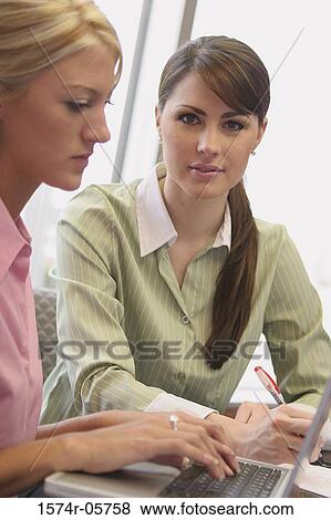 Stock Photo - Two businesswomen sitting in front of a laptop. Fotosearch