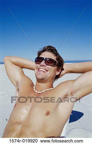 Stock Image - Close-up of a young man smiling on the beach. Fotosearch