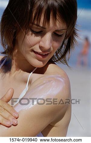 Stock Image - Close-up of a young woman applying suntan lotion on her arm. Fotosearch