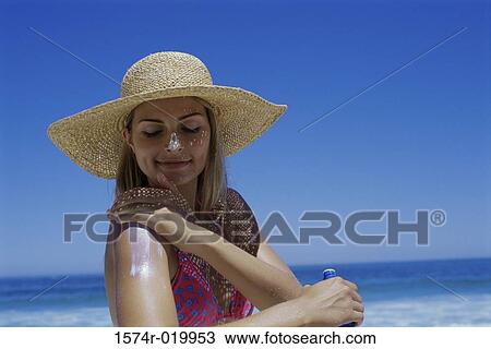 Close-up of a young woman applying suntan lotion on her shoulder View Large Photo Image Stock Image - Close-up of a young woman applying suntan lotion on her shoulder. Fotosearch