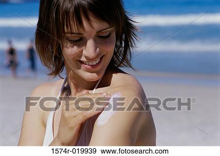 Close-up of a young woman applying suntan lotion on her shoulder View Large Photo Image Stock Photo - Close-up of a young woman applying suntan lotion on her shoulder. Fotosearch