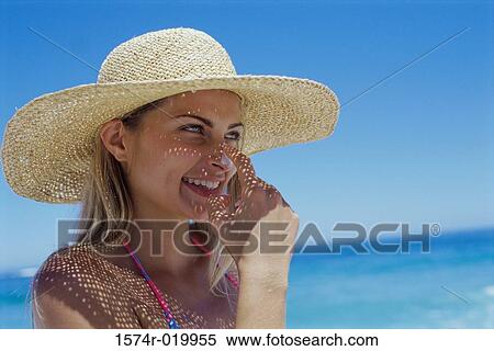 Stock Photography - Close-up of a young woman applying suntan lotion to her nose. Fotosearch
