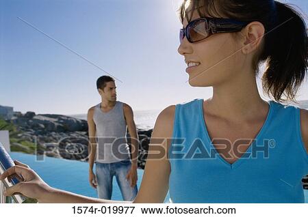 Close-up of a young woman with a young man standing behind her View Large Photo Image Stock Photo - Close-up of a young woman with a young man standing behind her. Fotosearch
