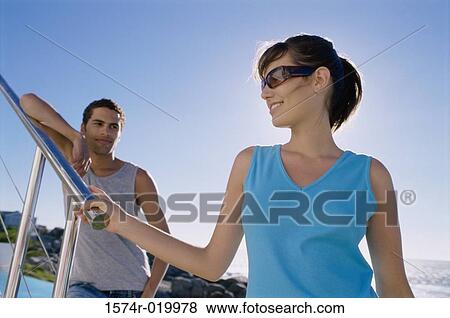 Stock Photo - Close-up of a young woman with a young man standing behind her. Fotosearch