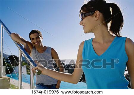 Stock Photograph - Close-up of a young woman with a young man standing behind her. Fotosearch