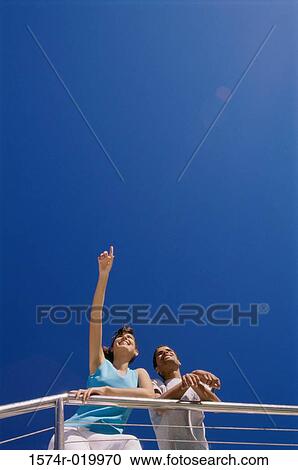 Low angle view of a young couple leaning against a railing View Large Photo Image Stock Image - Low angle view of a young couple leaning against a railing. Fotosearch