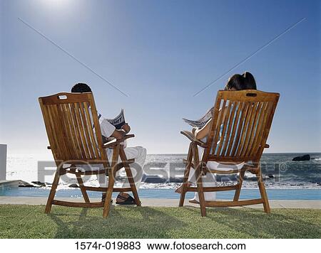 Rear view of a young couple sitting on chairs at the poolside View Large Photo Image Stock Image - Rear view of a young couple sitting on chairs at the poolside. Fotosearch