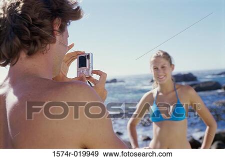 Rear view of a young man taking a photograph of a young woman View Large Photo Image Stock Photo - Rear view of a young man taking a photograph of a young woman. Fotosearch