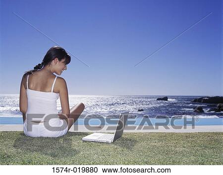 Rear view of a young woman looking at a laptop View Large Photo Image Stock Image - Rear view of a young woman looking at a laptop. Fotosearch