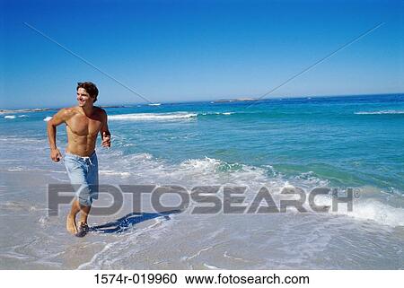 Young man running on the beach View Large Photo Image Stock Image - Young man running on the beach. Fotosearch