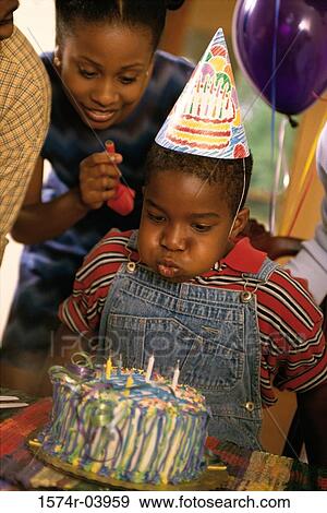 Stock Photo - Boy blowing out candles on his birthday cake. Fotosearch