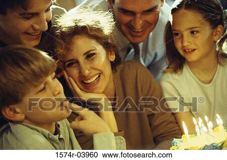 Stock Image - Boy licking icing off his fingers in front of a birthday cake. Fotosearch