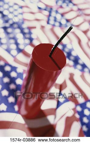 Stock Photograph - Close-up of a firecracker on American flags. Fotosearch