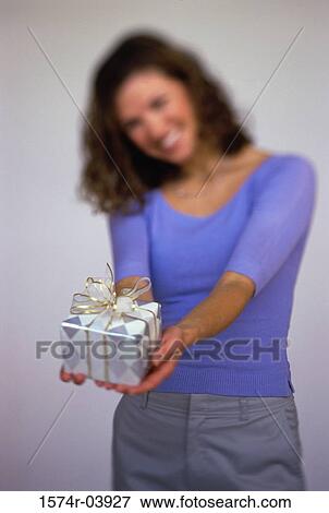Close-up of a young woman holding out a gift View Large Photo Image Stock Photo - Close-up of a young woman holding out a gift. Fotosearch