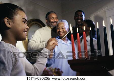 Stock Image - Girl lighting candles to celebrate Kwanzaa. Fotosearch