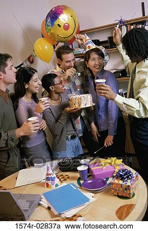 Stock Image - Group of business executives celebrating a birthday in the office. Fotosearch