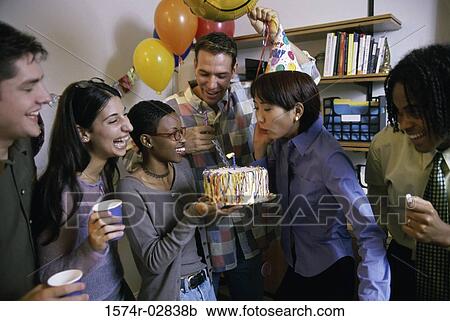 Stock Image - Group of business executives celebrating a birthday in the office. Fotosearch