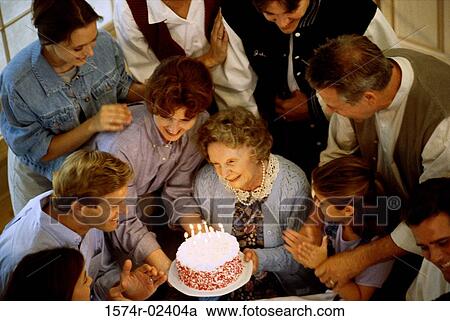 Stock Image - High angle view of a family in front of a birthday cake. Fotosearch