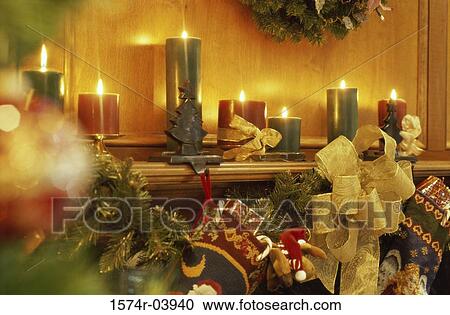 Stock Image - Lit candles and Christmas decorations on a mantelpiece. Fotosearch