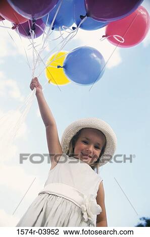 Low angle view of a girl holding balloons View Large Photo Image Stock Image - Low angle view of a girl holding balloons. Fotosearch