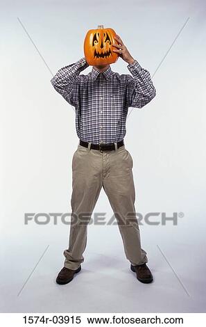 Stock Photography - Man holding a carved Halloween pumpkin in front of his face. Fotosearch