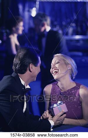 Stock Photo - Mid adult man handing a mid adult woman a gift. Fotosearch