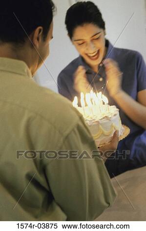 Mid adult man holding a birthday cake in front of a mid adult woman View Large Photo Image Stock Photography - Mid adult man holding a birthday cake in front of a mid adult woman. Fotosearch