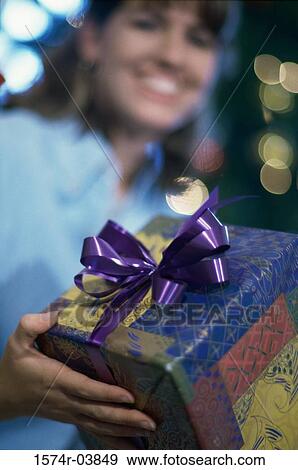 Mid adult woman holding a gift smiling View Large Photo Image Stock Photo - Mid adult woman holding a gift smiling. Fotosearch