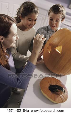 Mother carving a pumpkin with her son and daughter View Large Photo Image Stock Image - Mother carving a pumpkin with her son and daughter. Fotosearch