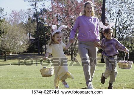 Stock Image - Mother walking on a lawn with her son and daughter. Fotosearch