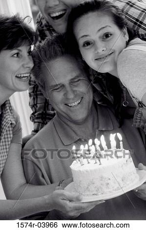 Stock Photograph - Parents with their son and daughter in front of a birthday cake. Fotosearch