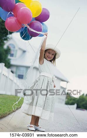 Stock Image - Portrait of a girl holding balloons. Fotosearch