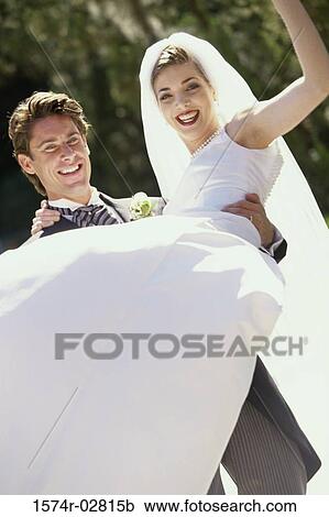 Stock Image - Portrait of a groom lifting his bride. Fotosearch