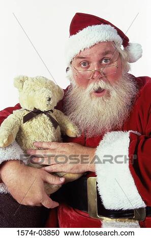 Stock Image - Portrait of Santa Claus holding a teddy bear. Fotosearch